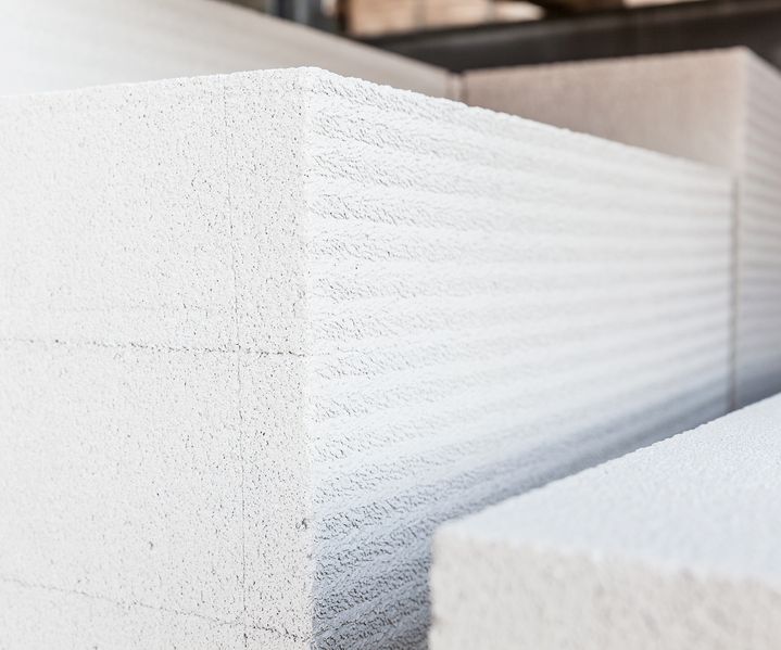 Mehrere weiße Porenbetonsteine liegen gestapelt im Baustofflager, die Struktur der Oberfläche ist gut erkennbar.