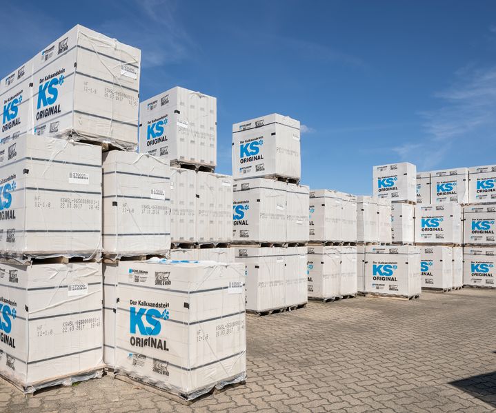 Mehrere Kalksandsteine sind sauber gestapelt, die helle, glatte Oberfläche und die scharfkantigen Formen sind gut erkennbar.