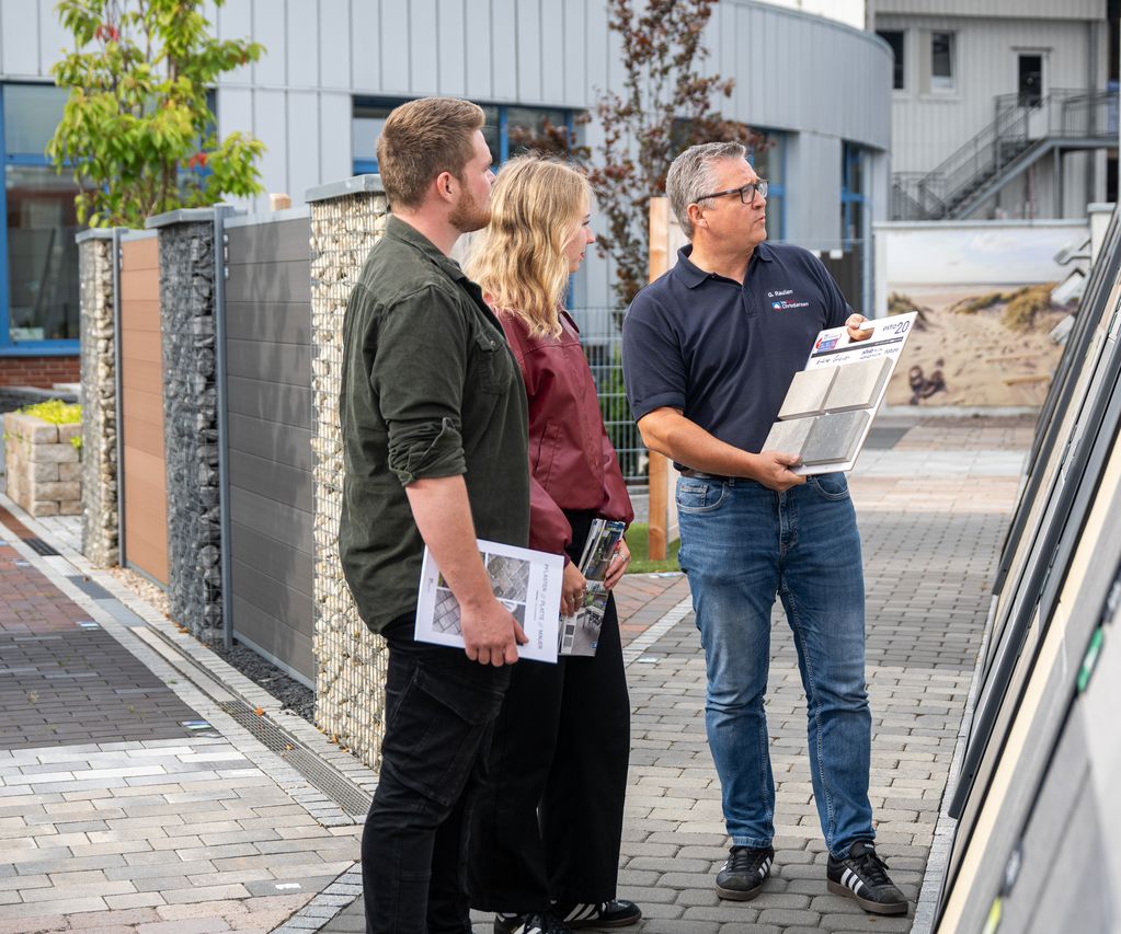 Kunde und Fachberater stehen vor Musterflächen und besprechen die Gestaltung einer Terrasse.