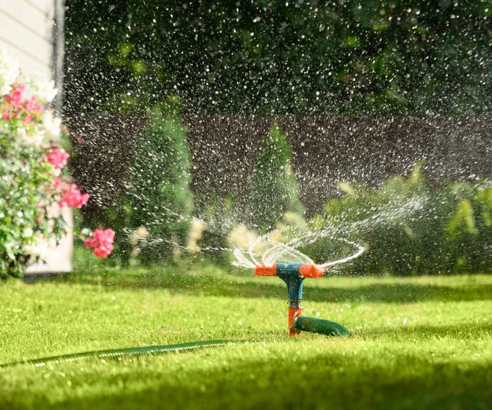 Ein Rasensprenger verteilt Wasser gleichmäßig über eine Grünfläche.