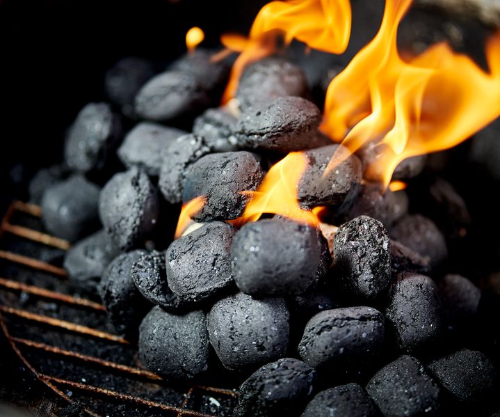 Grillkohle und Anzünder liegen bereit für das Entzünden eines Grills im Außenbereich.
