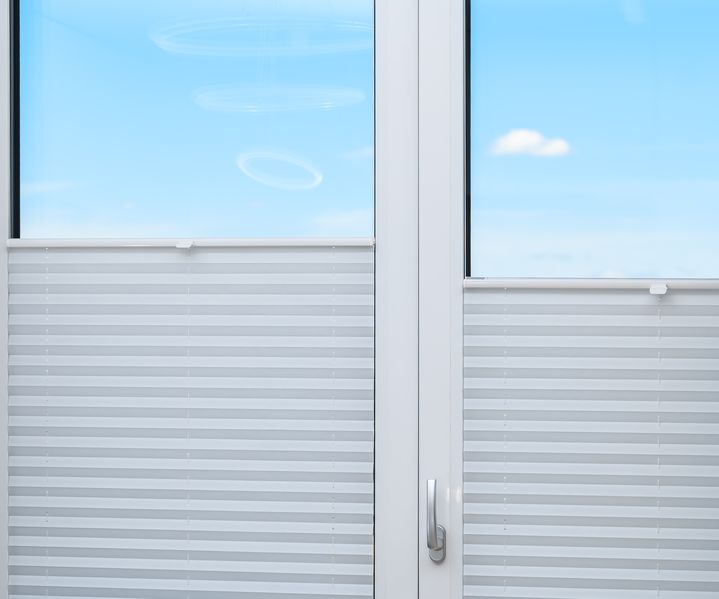 Ein Plissee ist am Fenster angebracht und ermöglicht flexiblen Sicht- und Sonnenschutz im Innenraum