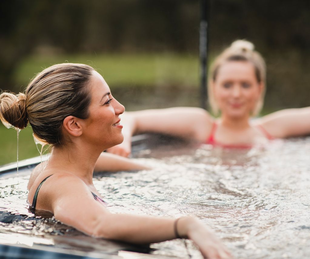 Ein gemütlicher Whirlpool steht im Garten zwischen Pflanzen und lädt zum Entspannen ein.