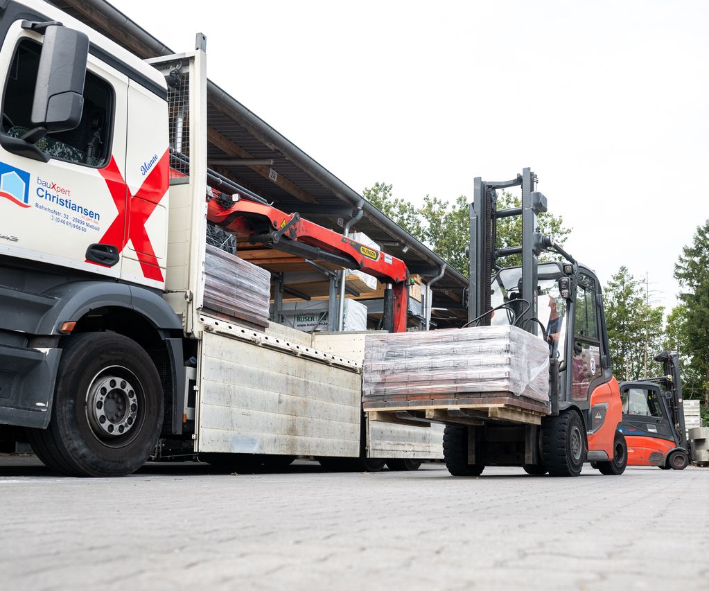 Ein Stapler hebt Material von einem Lagerplatz auf einen LKW.