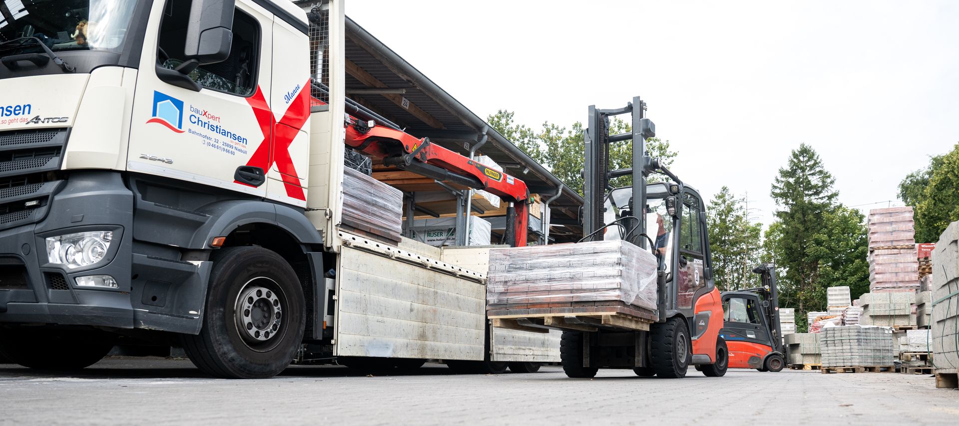 Ein Stapler hebt Material von einem Lagerplatz auf einen LKW.