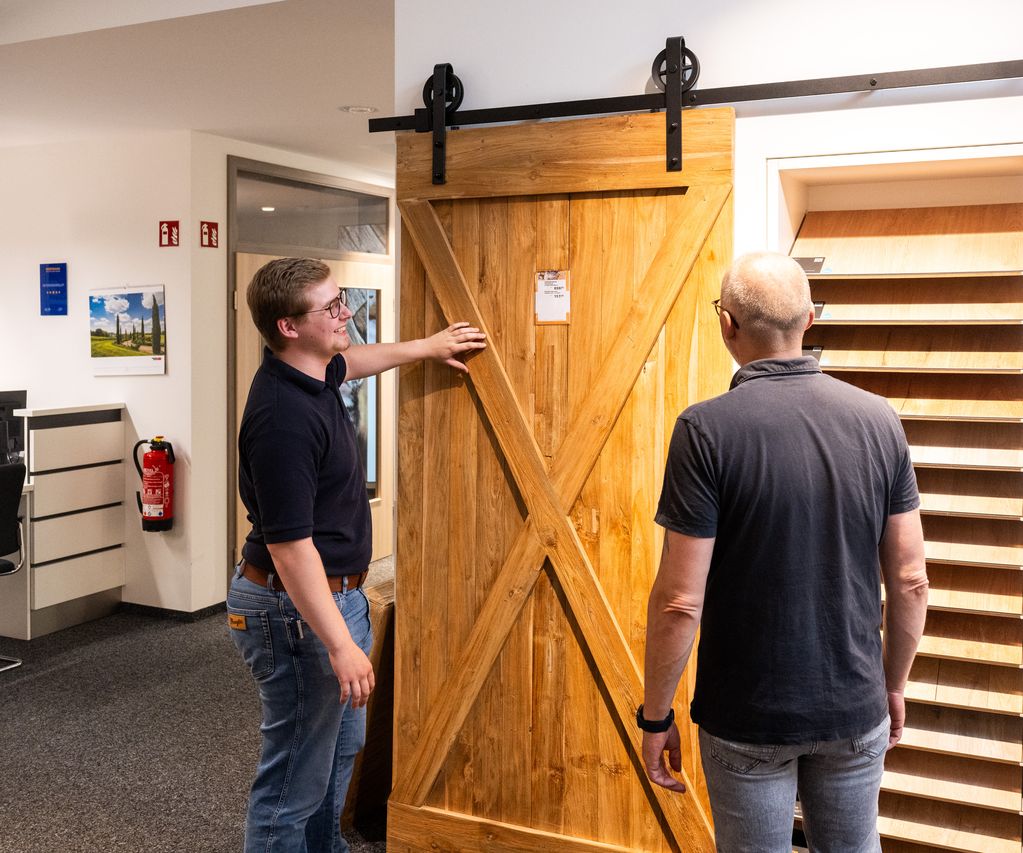 Ein Mitarbeiter berät ein Kundengespräch direkt vor einer ausgestellten Innentür zu Ausstattung und Design.