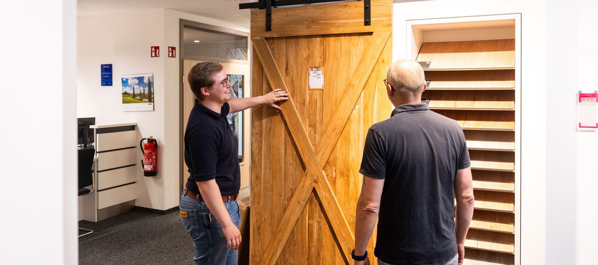 Ein Mitarbeiter berät ein Kundengespräch direkt vor einer ausgestellten Innentür zu Ausstattung und Design.