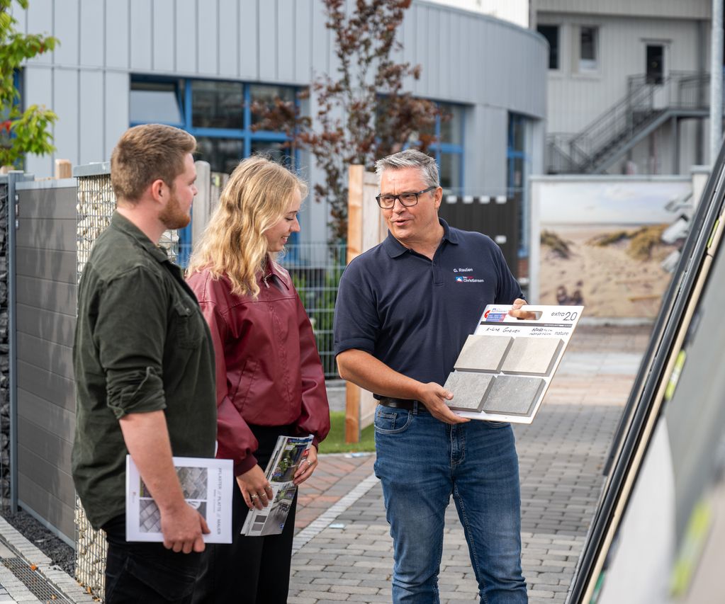Kunde und Fachberater stehen vor Musterflächen und besprechen die Gestaltung einer Terrasse.