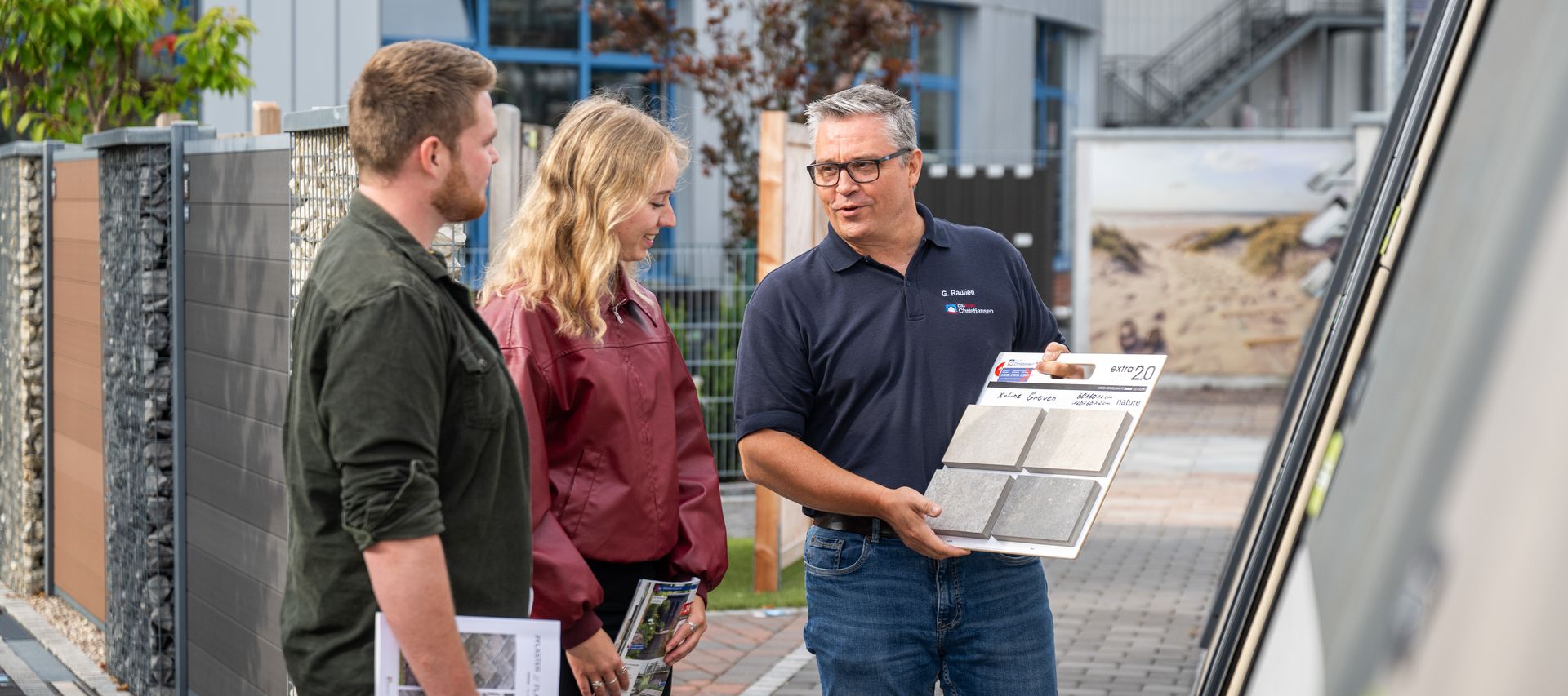 Kunde und Fachberater stehen vor Musterflächen und besprechen die Gestaltung einer Terrasse.