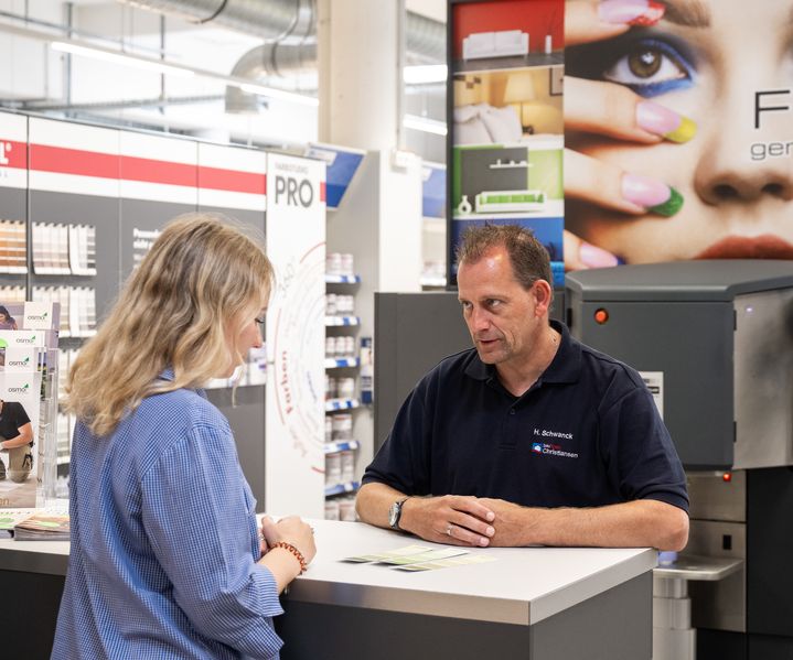 Eine Kundin wird an der Farbmischanlage zu individuellen Wunschfarbtönen beraten.