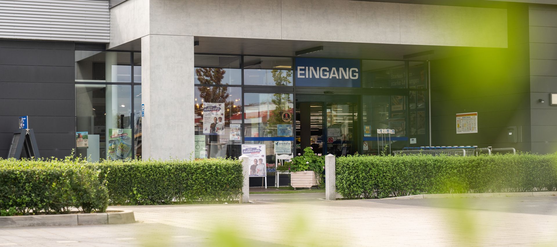 Die Außenansicht mit Eingangsbereich und Beschilderung lädt Kunden zum Besuch des Fachmarkts ein.