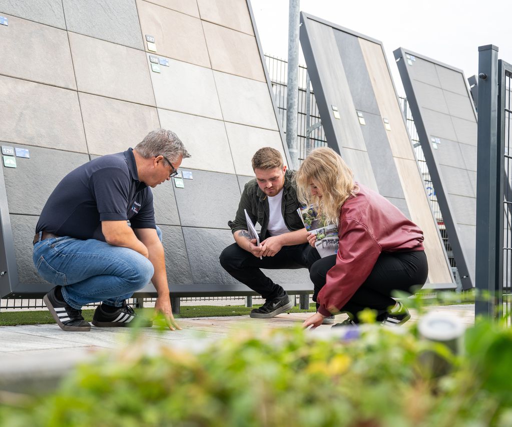 Ein Mitarbeiter berät Kunden im Ausstellungsbereich zu passenden Zaun- und Terrassenlösungen.