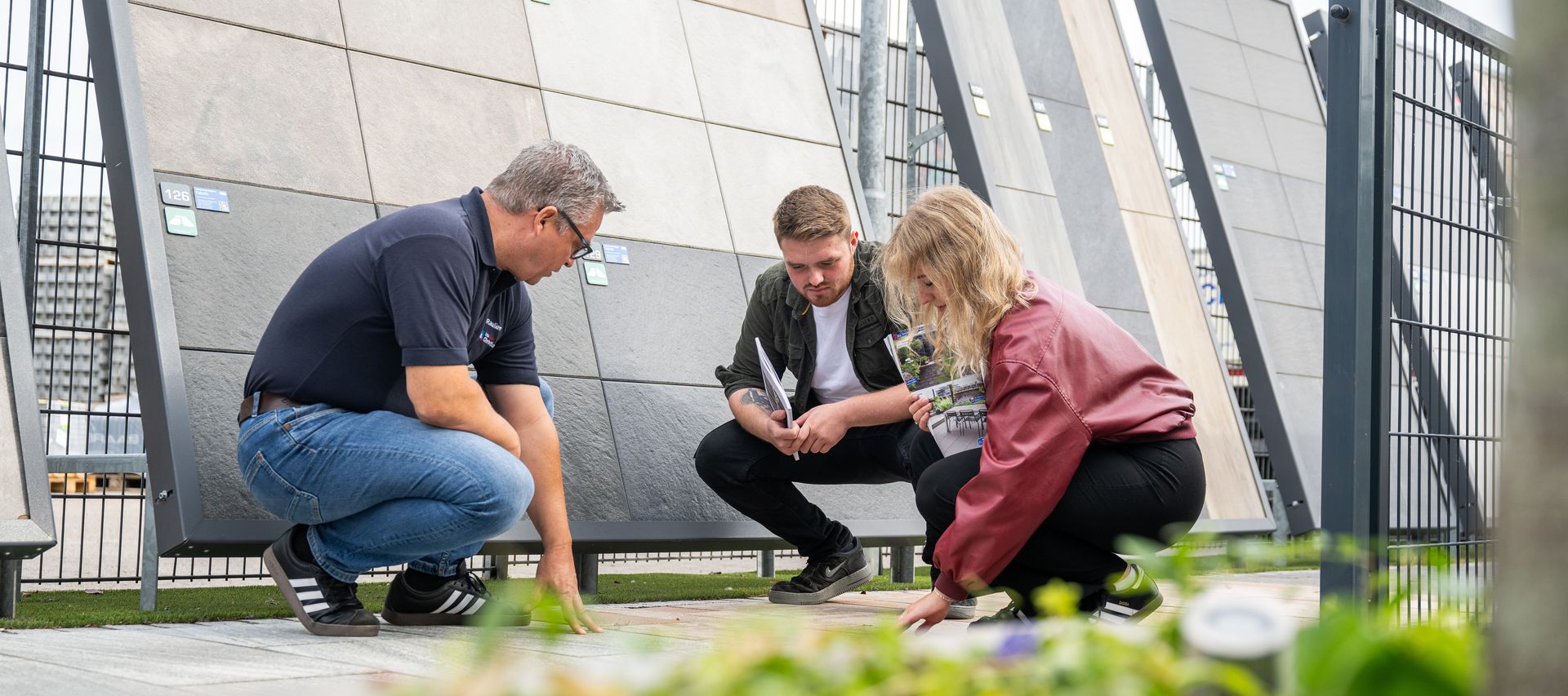 Ein Mitarbeiter berät Kunden im Ausstellungsbereich zu passenden Zaun- und Terrassenlösungen.