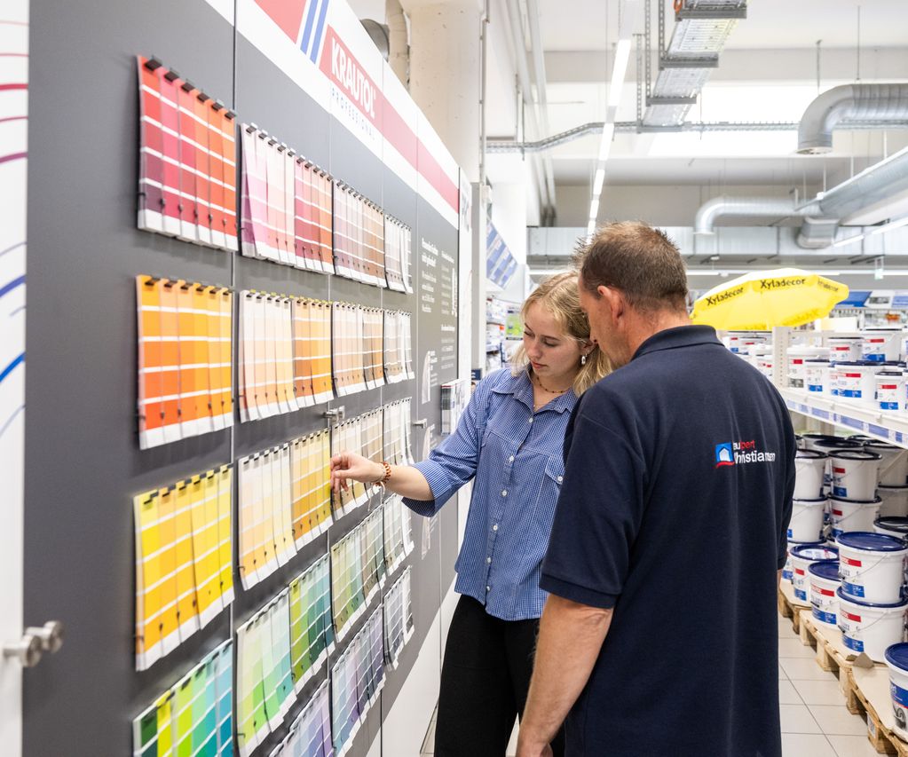 Eine Kundin vergleicht unterschiedliche Wandfarben und erhält Unterstützung bei der Produktauswahl.