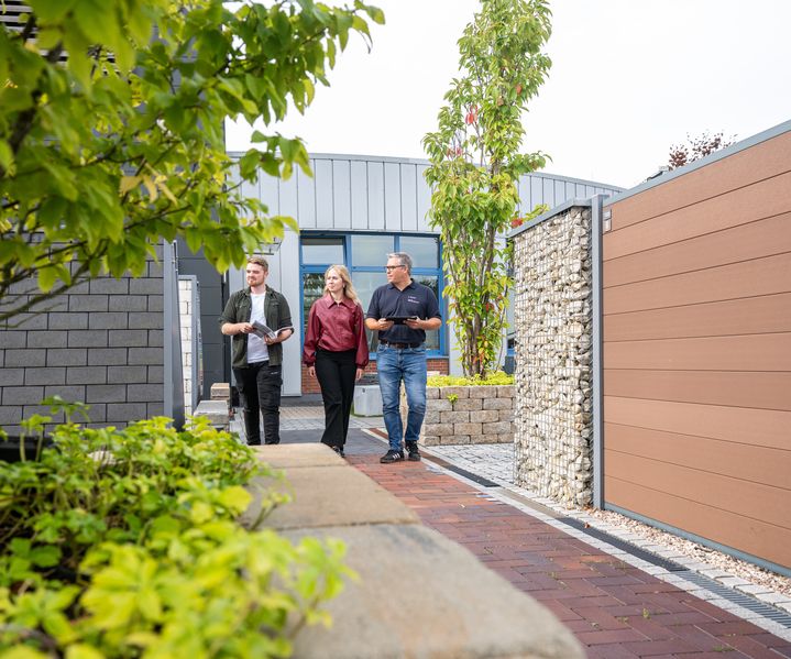 Ein Mitarbeiter berät Kunden im Ausstellungsbereich zu passenden Zaun- und Terrassenlösungen.