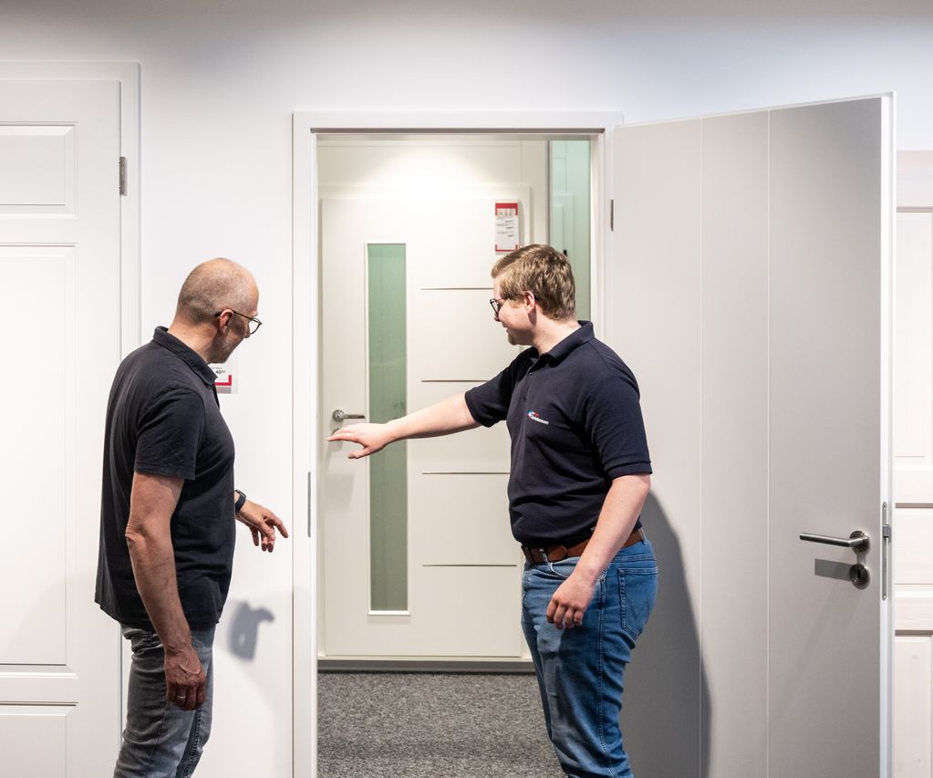 Ein Berater zeigt Details wie Schließmechanismus und Oberflächenstruktur an einer Ausstellungstür.