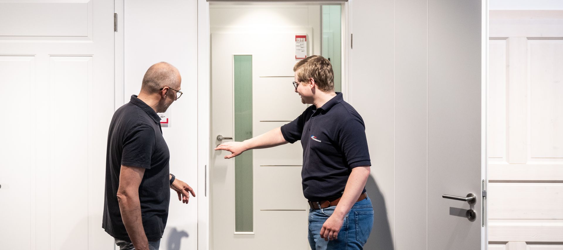Ein Berater zeigt Details wie Schließmechanismus und Oberflächenstruktur an einer Ausstellungstür.