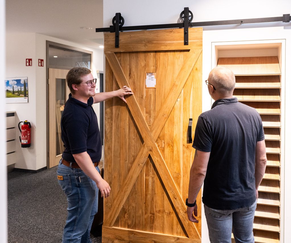 Ein Mitarbeiter berät ein Kundengespräch direkt vor einer ausgestellten Innentür zu Ausstattung und Design.