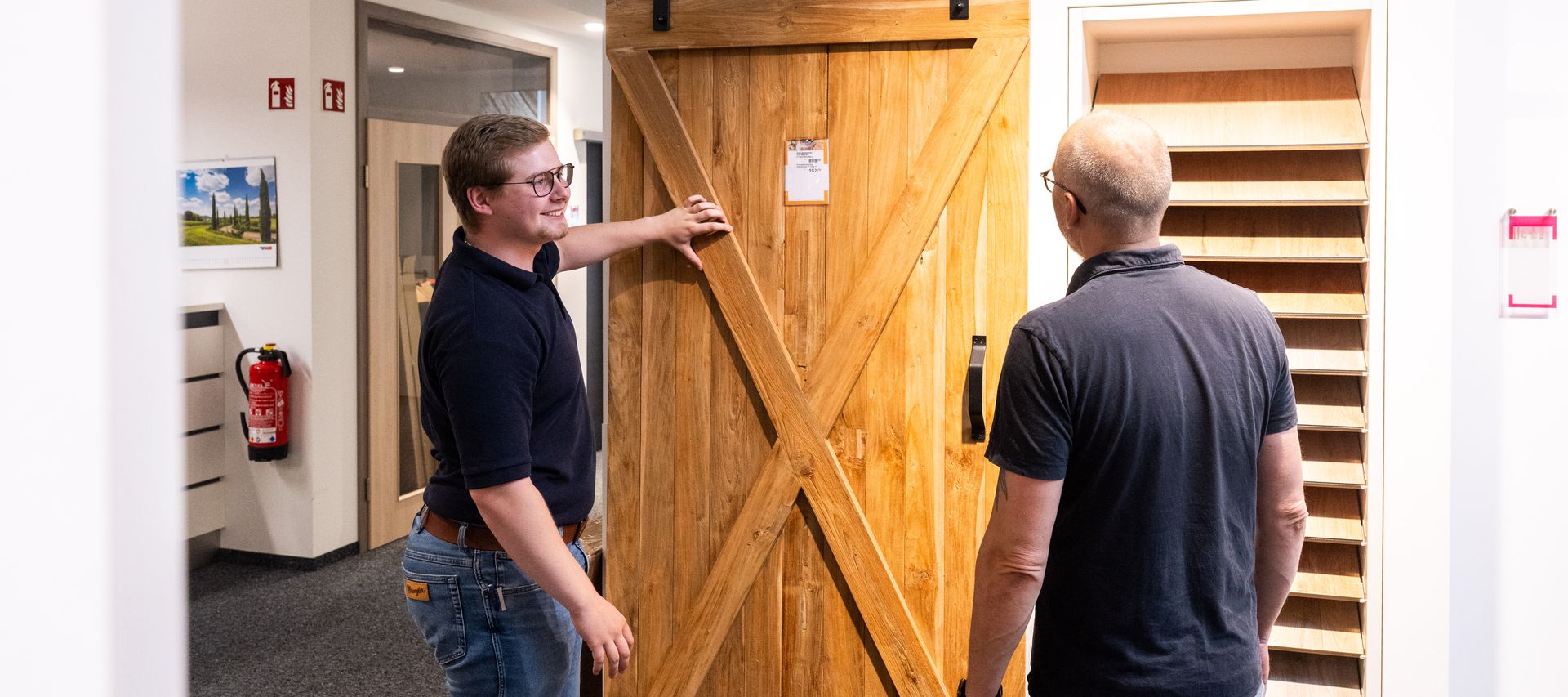 Ein Mitarbeiter berät ein Kundengespräch direkt vor einer ausgestellten Innentür zu Ausstattung und Design.