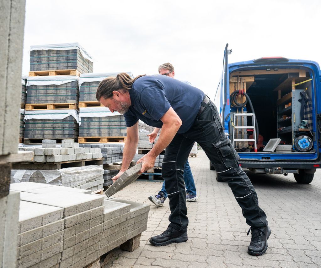 Ein Mitarbeiter erklärt einem Kunden die Eigenschaften von Pflastersteinen für den Außenbereich.