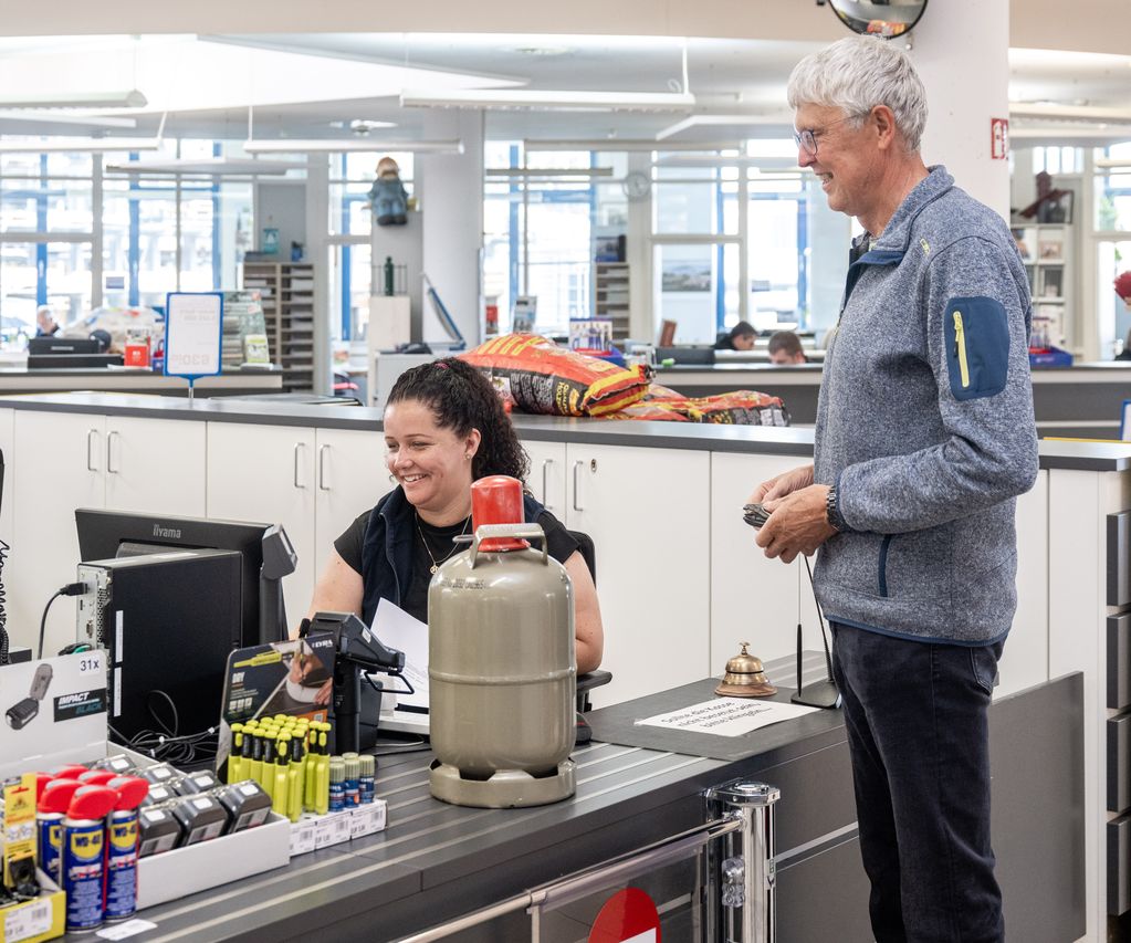 Kunde erhält eine Gasflasche vom Mitarbeiter an der Verkaufsstelle im Fachhandel.