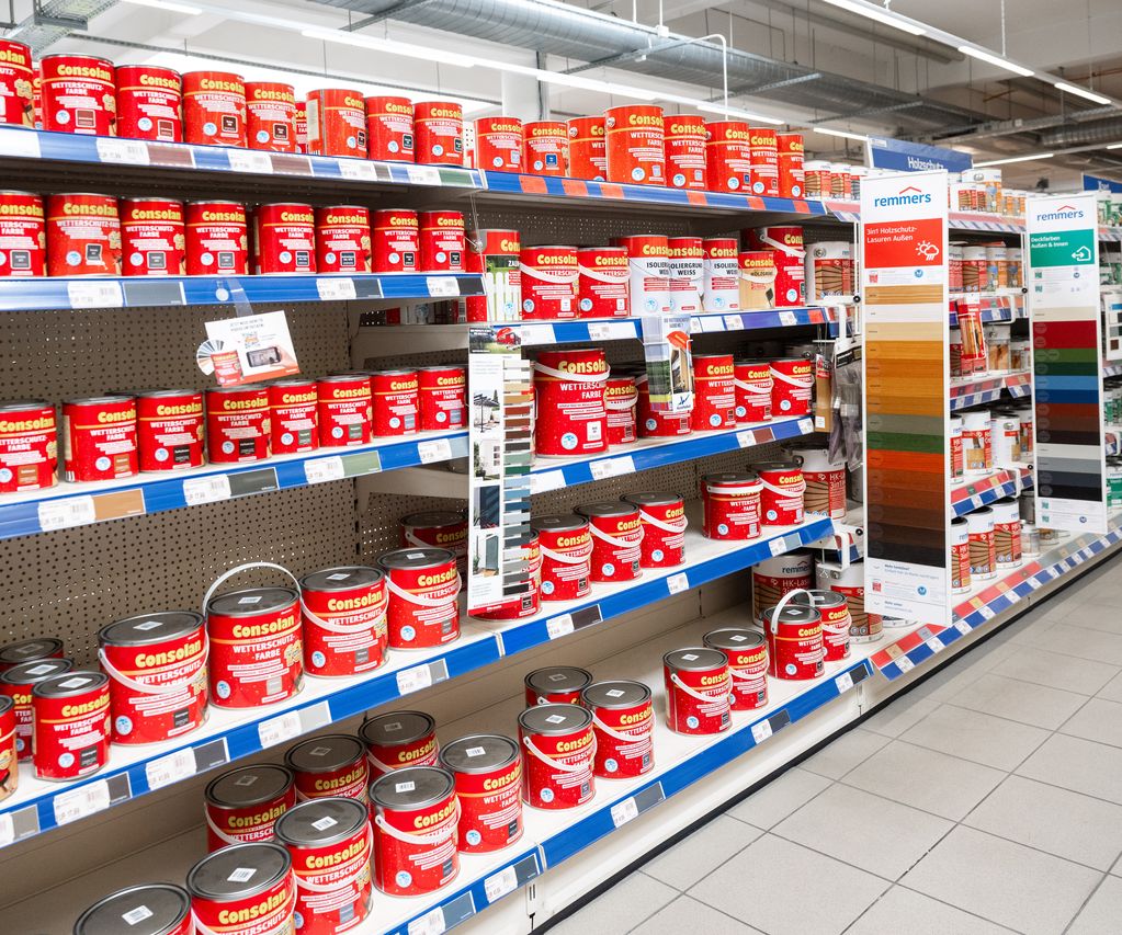 Ein Mitarbeiter erklärt einem Kunden die Unterschiede zwischen Holzlasur, Holzöl und Holzfarbe.