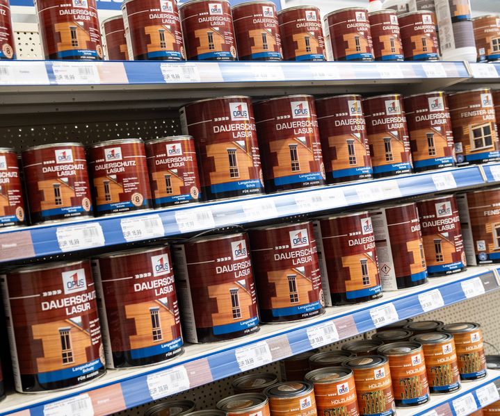 Regale mit verschiedenen Holzschutz- und Farbprodukten wie Lasuren, Ölen und Lacken im Fachmarkt.