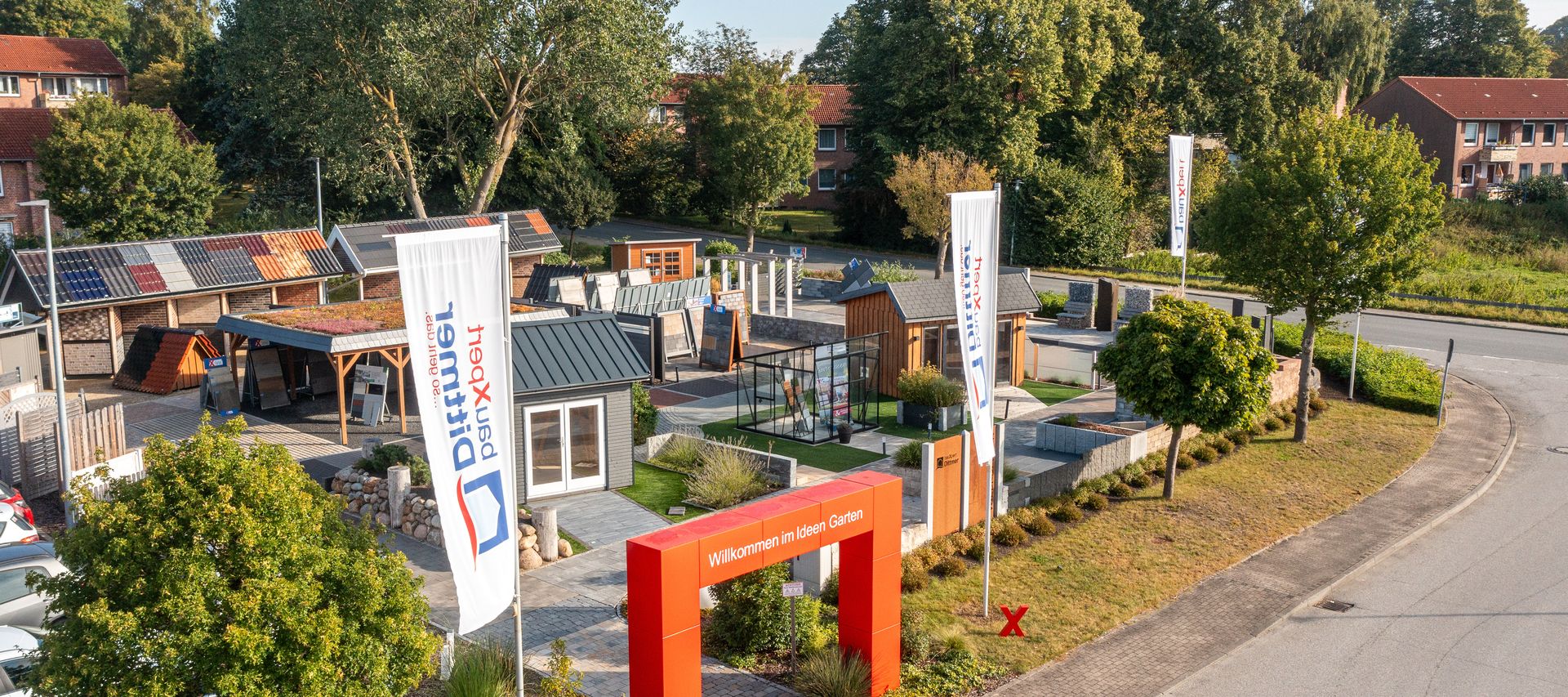 Luftaufnahme des Ideen-Gartens bei bauXpert Dittmer mit Musterhäusern, Ausstellungsflächen und Eingangstor mit rotem Bogen