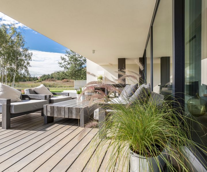Überdachte Holzterrasse mit Sitzgruppe und Pflanzkübeln an einem modernen Einfamilienhaus
