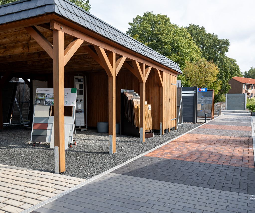Überdachte Musterfläche mit verschiedenen Terrassenbelägen und Zaunelementen in der Gartenausstellung von bauXpert Dittmer in Lütjenburg