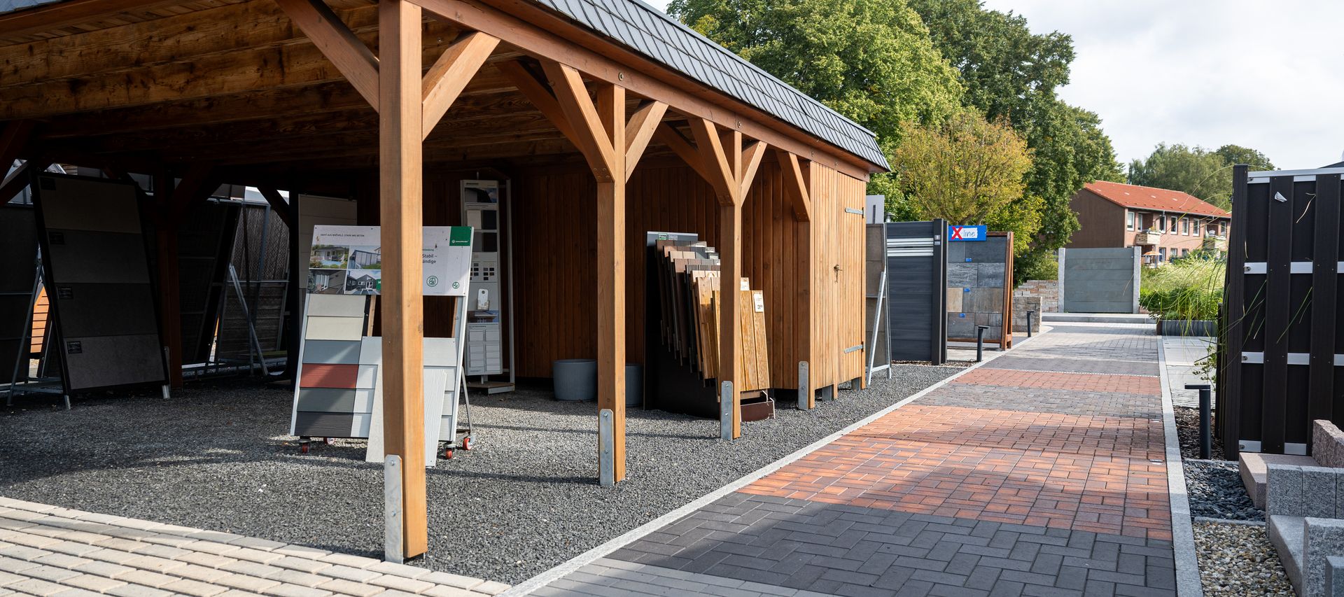Überdachte Musterfläche mit verschiedenen Terrassenbelägen und Zaunelementen in der Gartenausstellung von bauXpert Dittmer in Lütjenburg