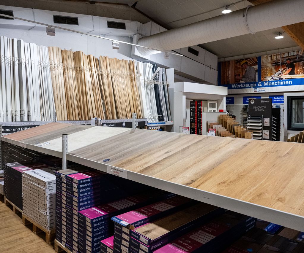 Innenaufnahme des Fachmarkts bei bauXpert Dittmer mit Auswahl an Bodenbelägen, Leisten, Profilholz und Maschinenbereich im Hintergrund