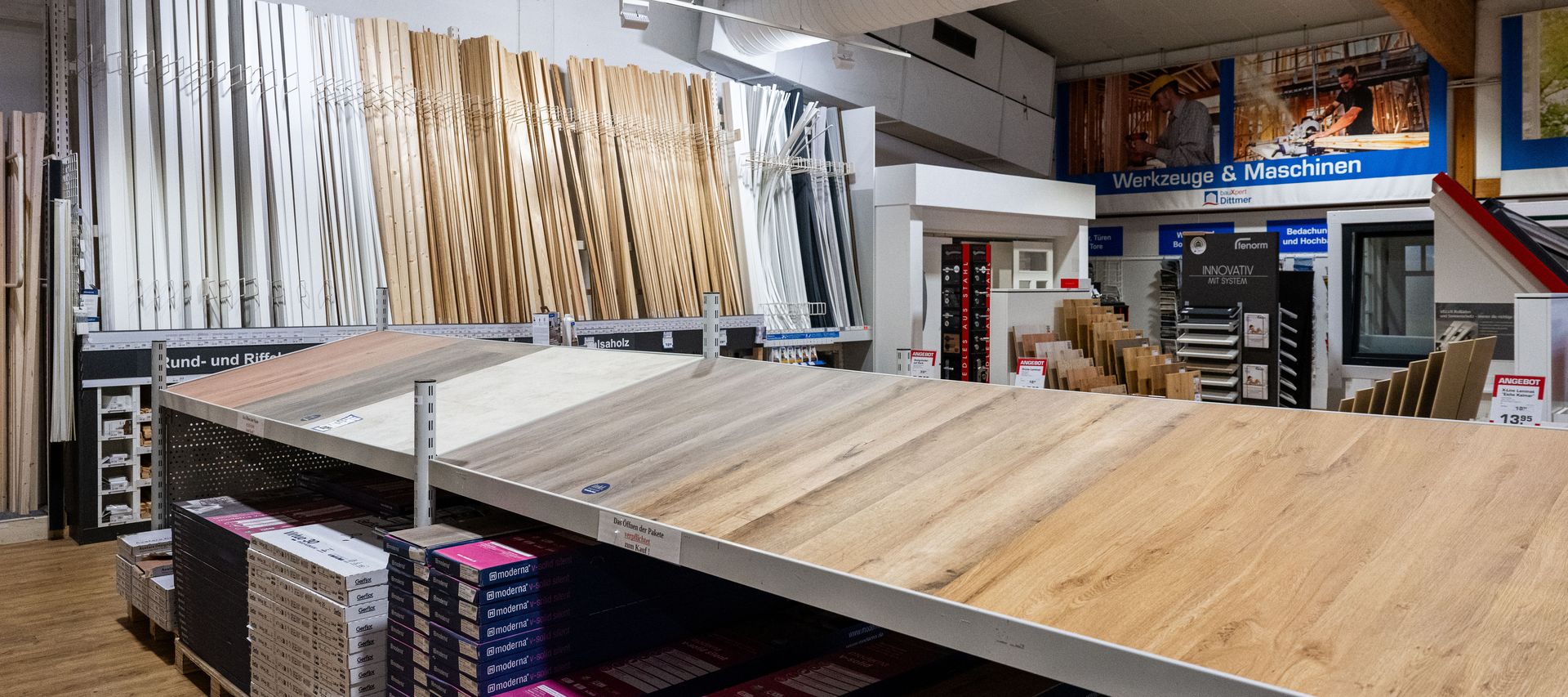 Innenaufnahme des Fachmarkts bei bauXpert Dittmer mit Auswahl an Bodenbelägen, Leisten, Profilholz und Maschinenbereich im Hintergrund