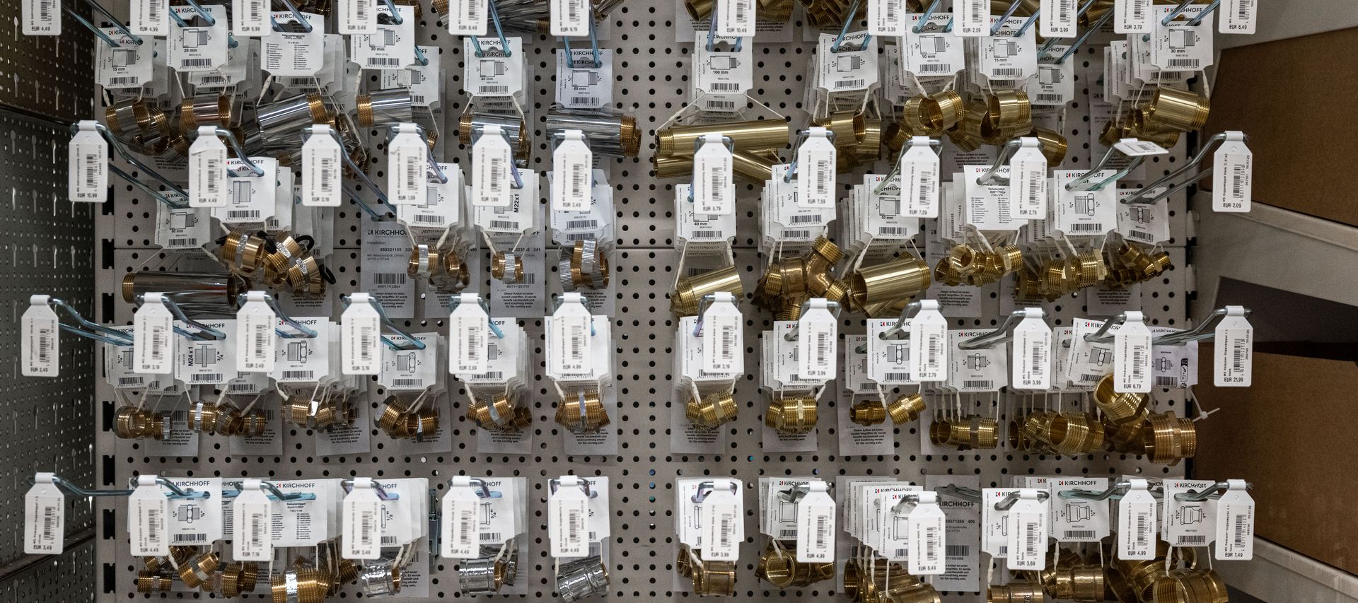 Nahaufnahme eines Verkaufsregals bei bauXpert Dittmer mit verschiedenen Messingfittings und Übergangsstücken für die Sanitärinstallation