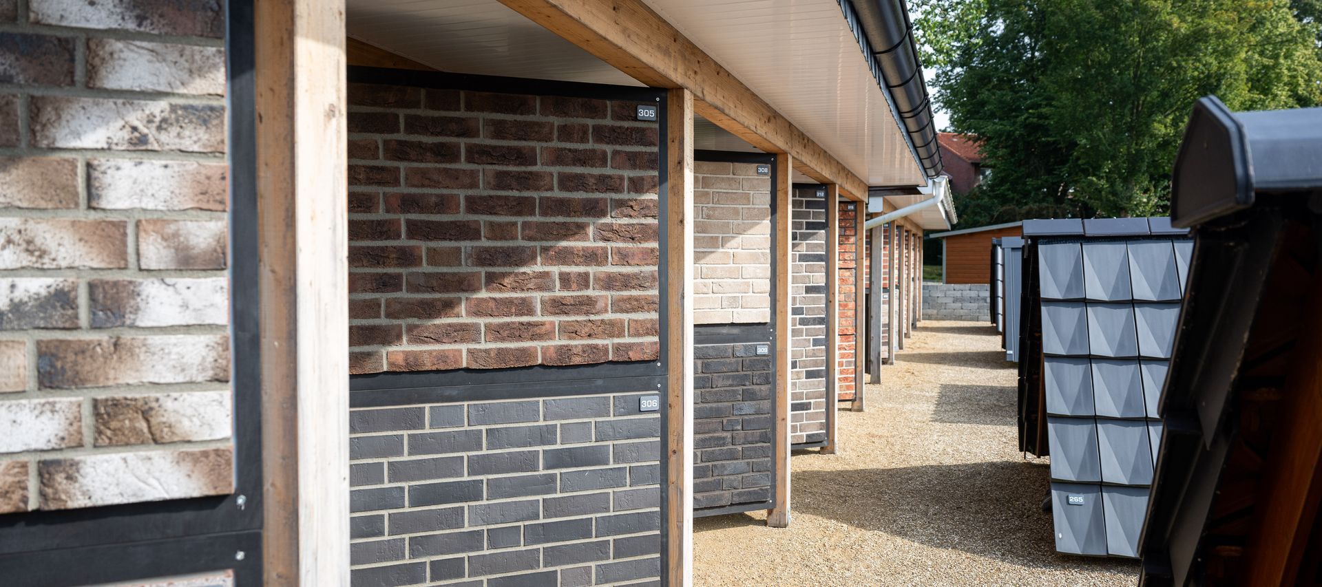 Musterwand mit verschiedenen Klinker- und Verblendstein-Varianten in der GaLa Ausstellung von bauXpert Dittmer, nummerierte Ausstellungsflächen unter einem Dach