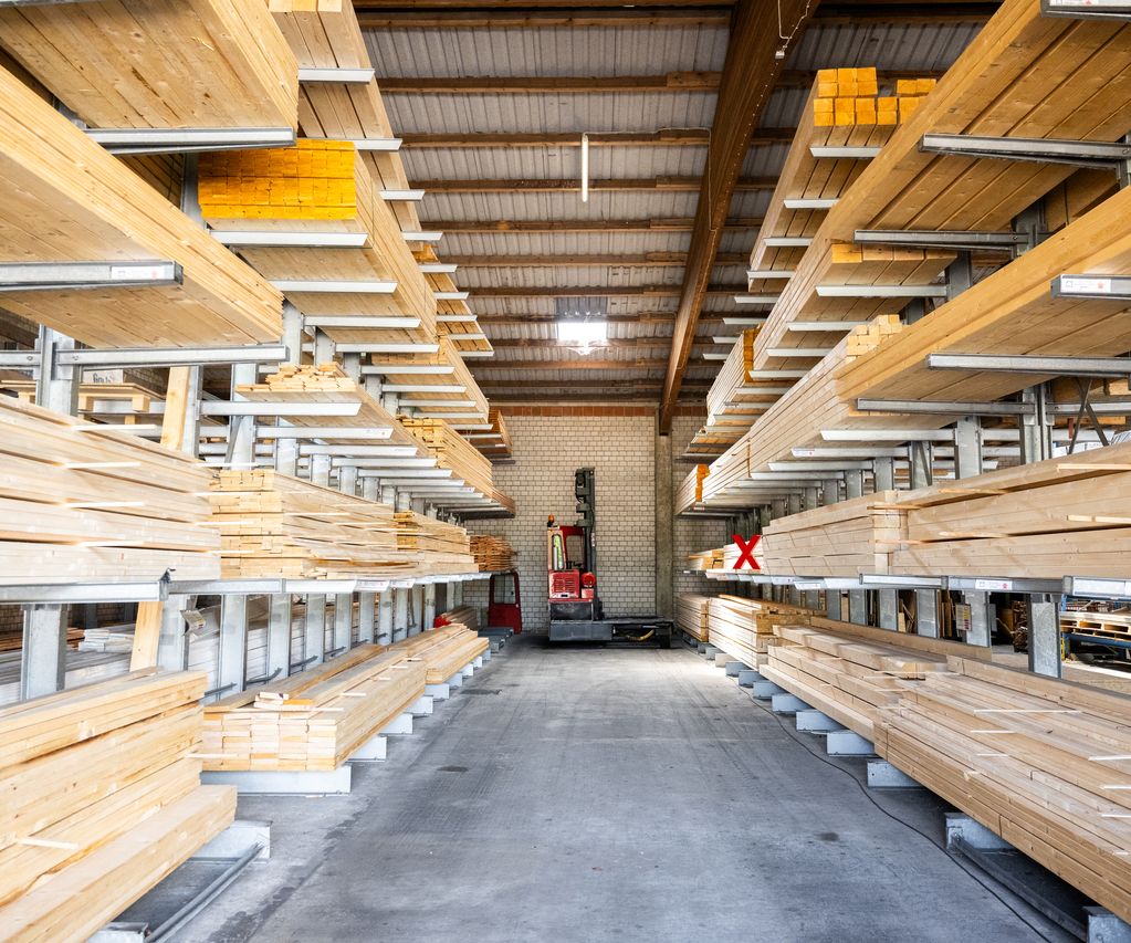 Holzlagerhalle mit Kragarmregalen voller Konstruktionsholz; Stapler am Gangende