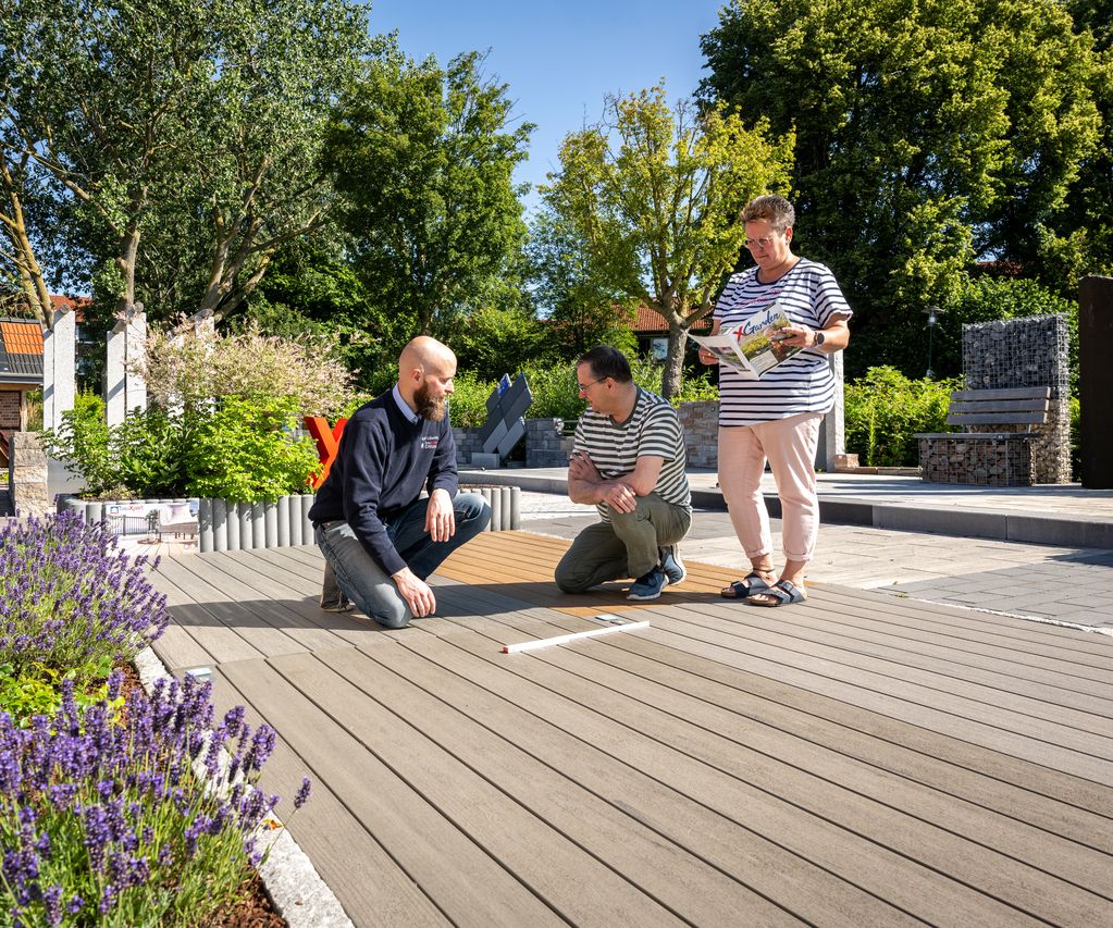 Mitarbeiter berät zwei Kunden zu Terrassendielen in der Gartenausstellung von bauXpert Dittmer in Lütjenburg