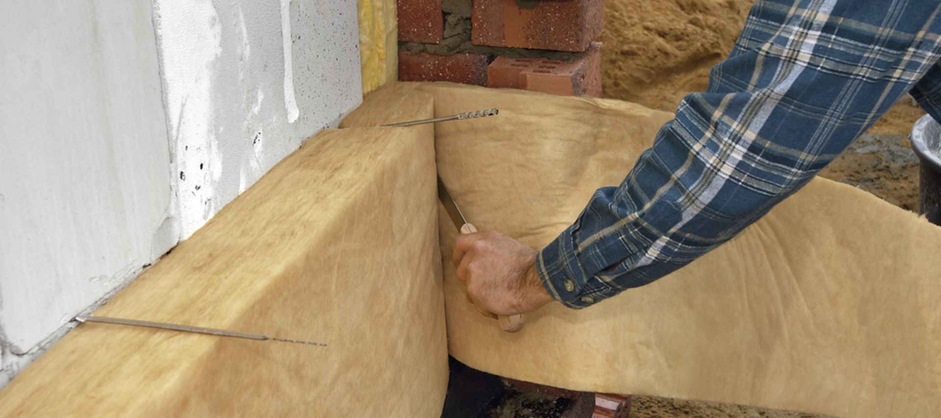 Arbeiter bringt Kerndämmmaterial an Hausfassade an