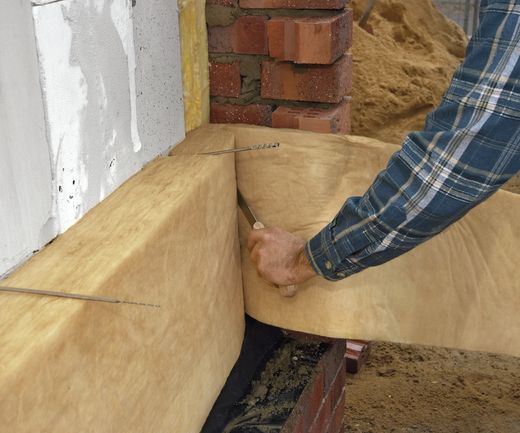 Arbeiter bringt Kerndämmmaterial an Hausfassade an