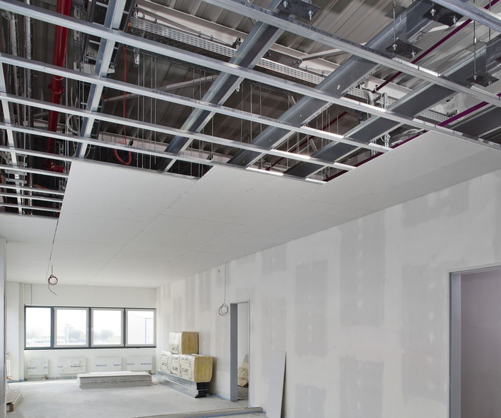 Trockenbauprofile werden in einem halbfertigen raum gezeigt die Decke ist nur zur hälfte it Gipskartonplatten bestückt die Trockenbauprofile bilden die Unterkonstruktion
