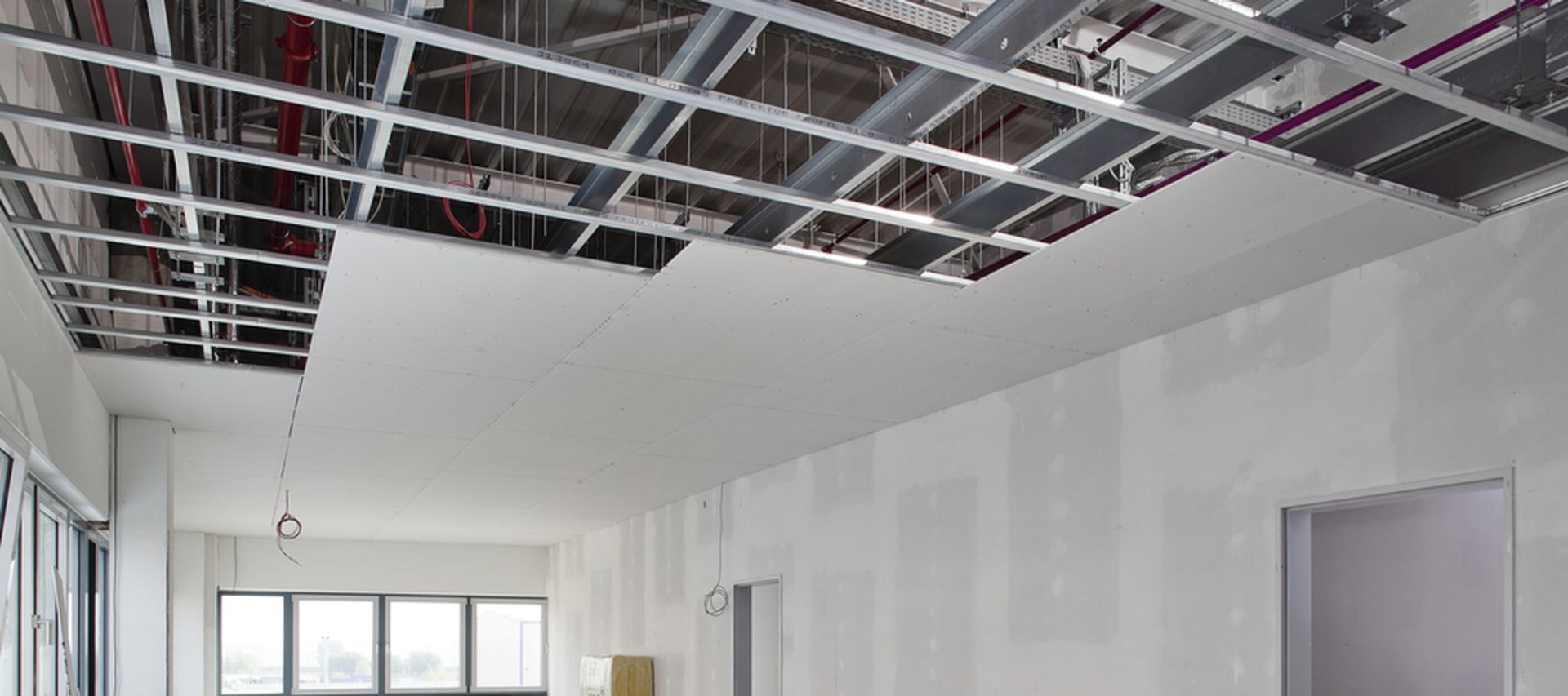 Trockenbauprofile werden in einem halbfertigen raum gezeigt die Decke ist nur zur hälfte it Gipskartonplatten bestückt die Trockenbauprofile bilden die Unterkonstruktion