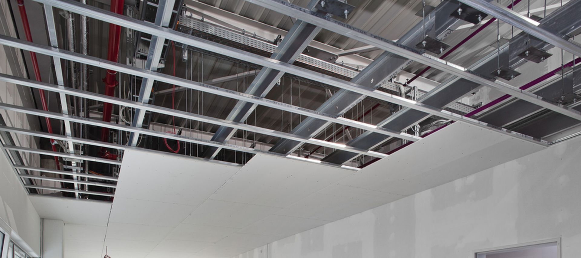 Trockenbauprofile werden in einem halbfertigen raum gezeigt die Decke ist nur zur hälfte it Gipskartonplatten bestückt die Trockenbauprofile bilden die Unterkonstruktion