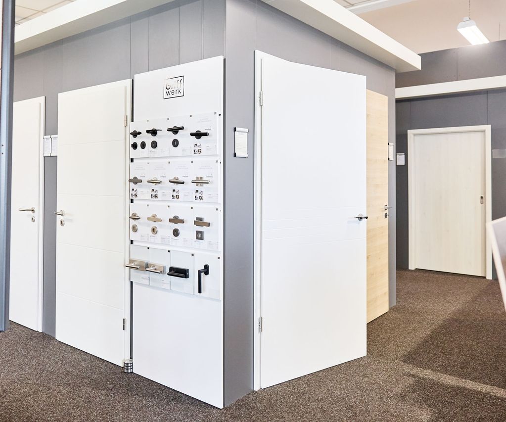 Einblick in die Türenausstellung von bauXpert Gebhard. Weiße Zimmertüren und Türgriffe werden als Muster zum verkauf gezeigt.