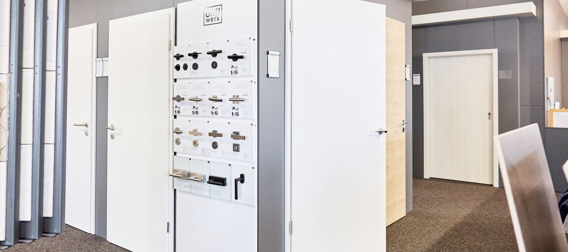 Einblick in die Türenausstellung von bauXpert Gebhard. Weiße Zimmertüren und Türgriffe werden als Muster zum verkauf gezeigt.