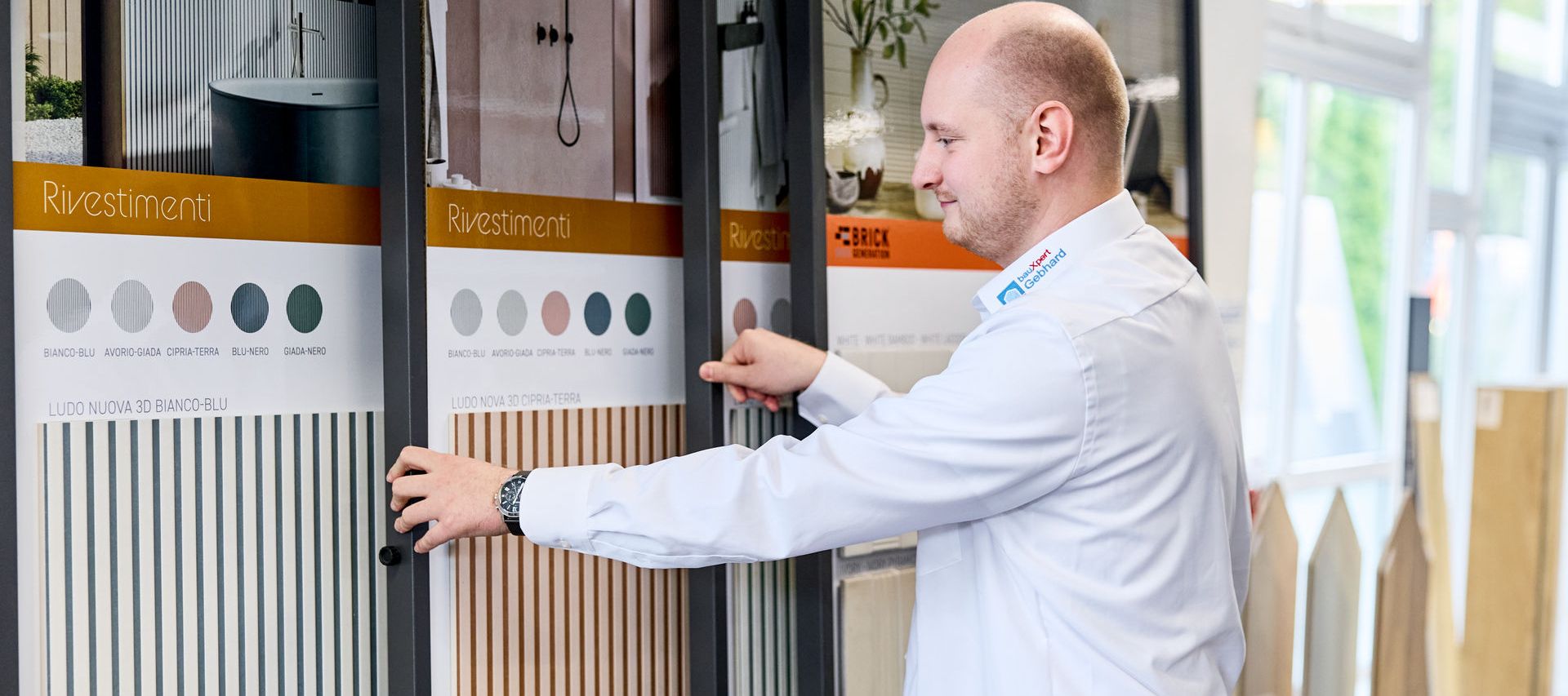 Ein Fliesenberater mit weißem Hemd betrachtet Fliesenmuster, die auf Tafeln in einer Fliesenausstellung bei Bremen präsentiert werden