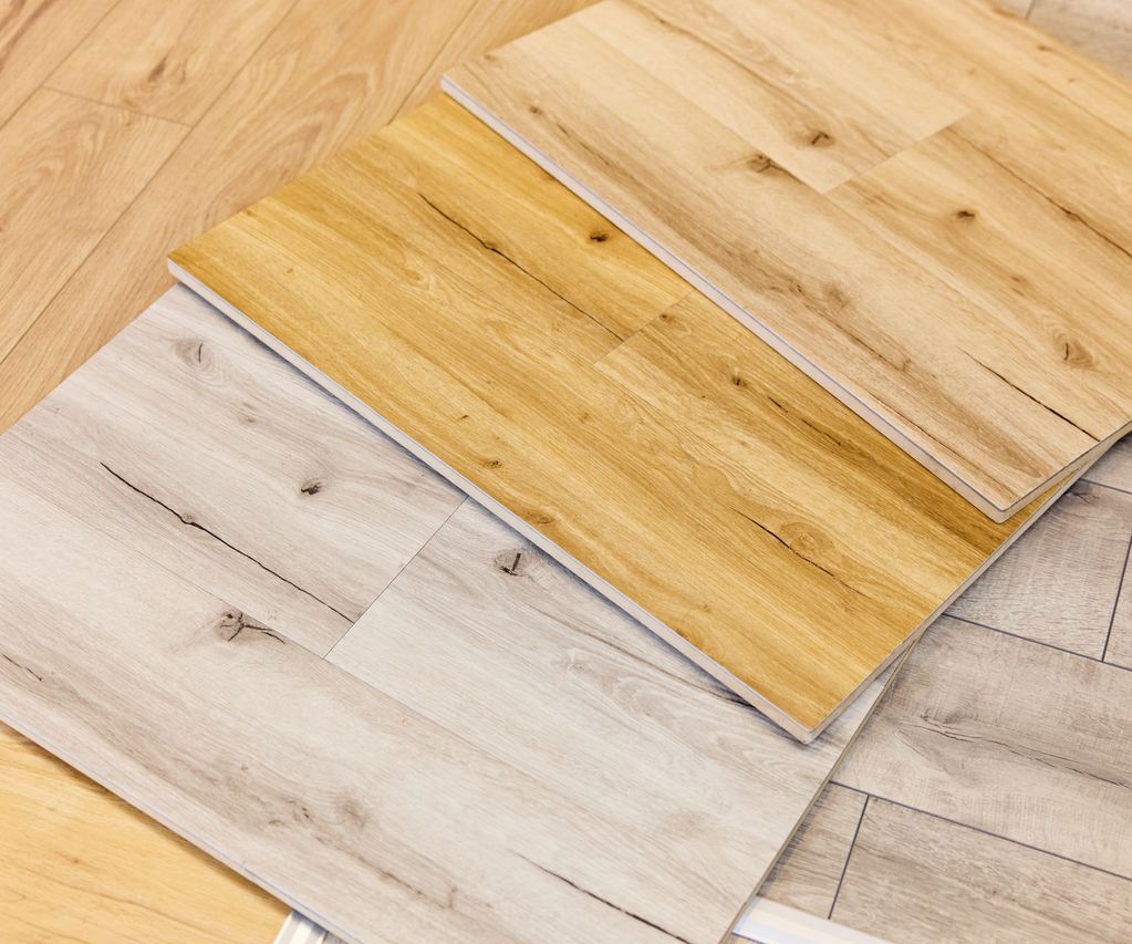 Laminat Bodenmuster in verschiedenen Holzfarbtönen, darunter helle und mittelbraune Töne, angeordnet auf einer Holzoberfläche.