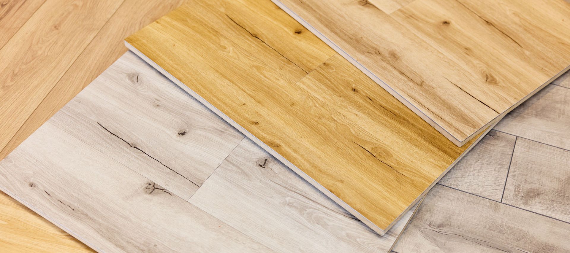 Laminat Bodenmuster in verschiedenen Holzfarbtönen, darunter helle und mittelbraune Töne, angeordnet auf einer Holzoberfläche.