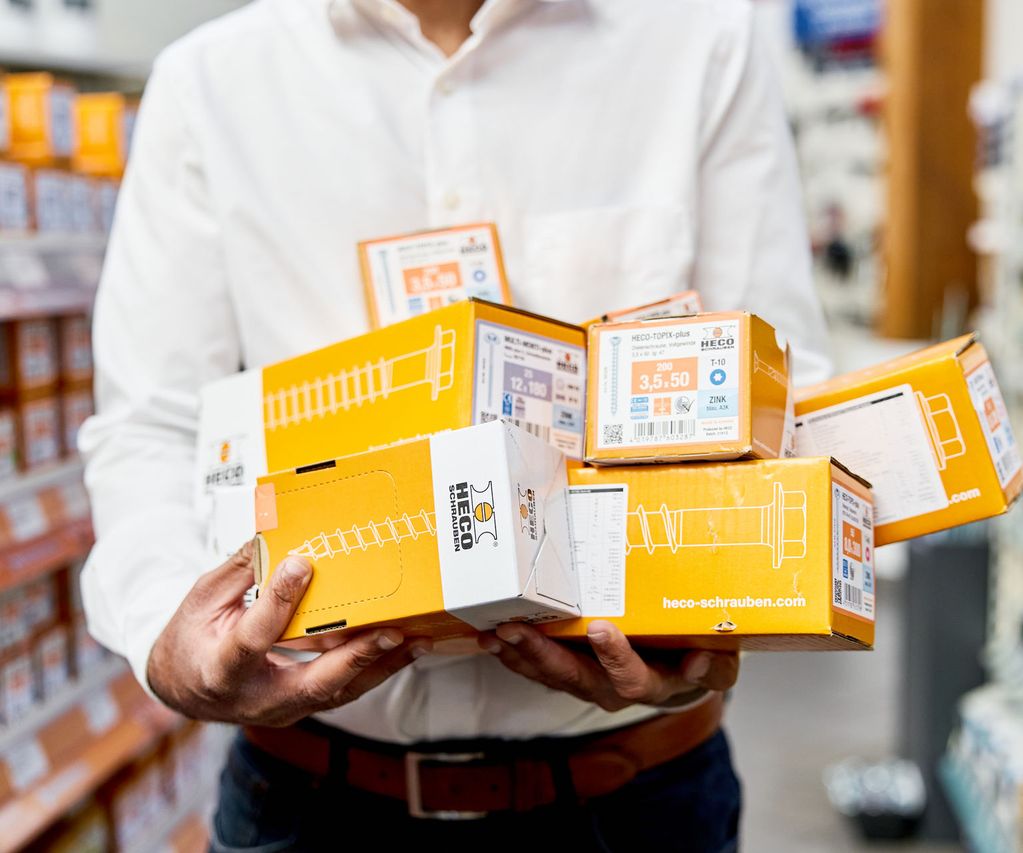 Schraubenpakete beim Verkäufer von bauXpert Gebhard im Arm bereit zum Verkauf