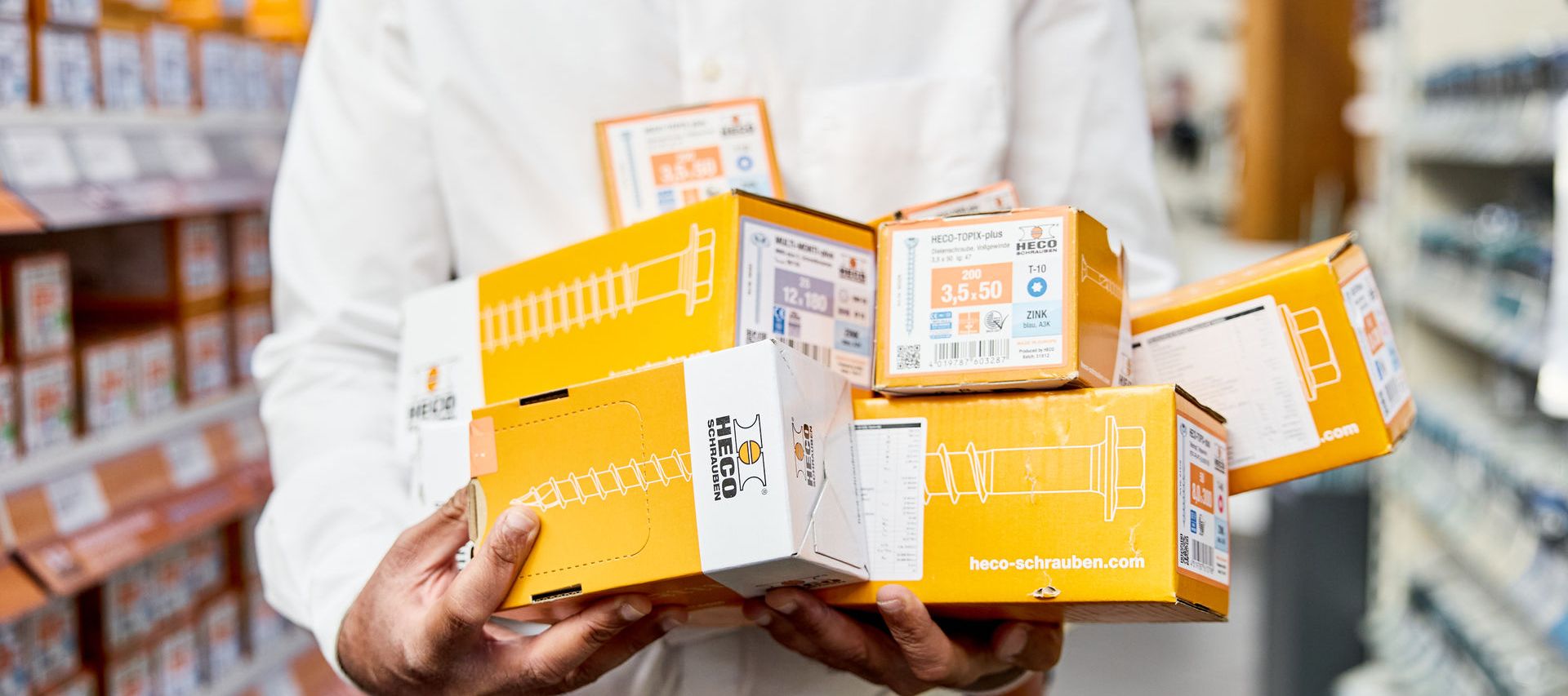 Schraubenpakete beim Verkäufer von bauXpert Gebhard im Arm bereit zum Verkauf