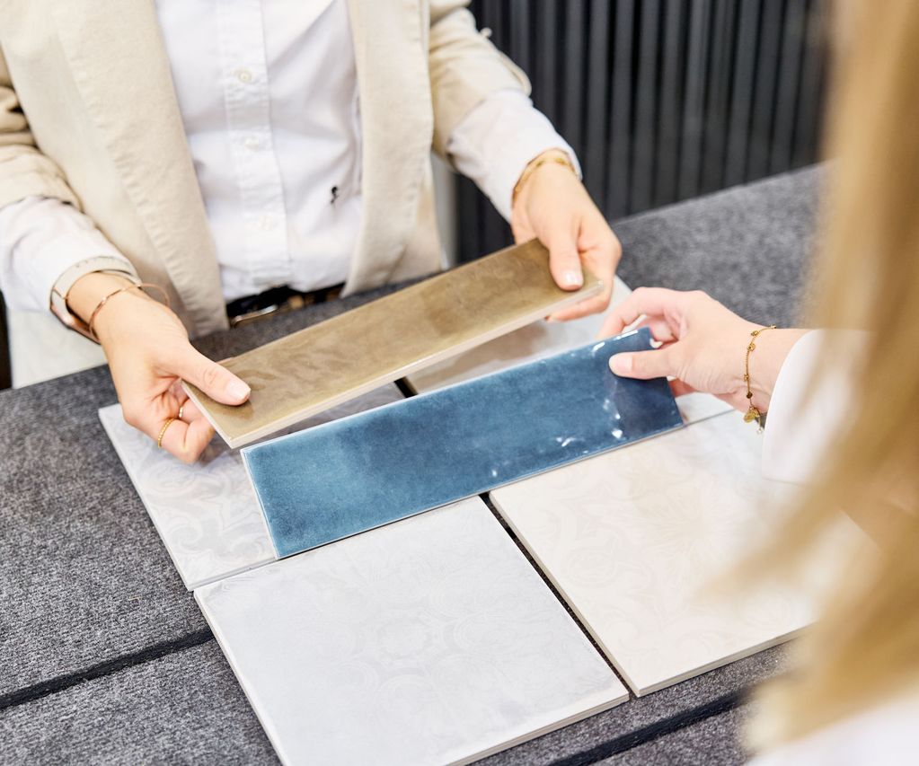 blaue und beige Fliesenmuster werden in der Hand gehalten und dem Kunden zum Fliesenkauf angeboten